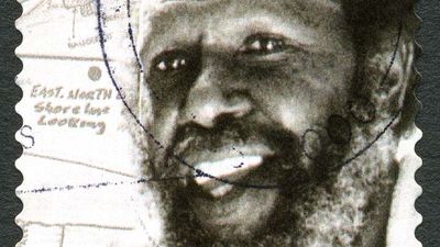 A used postage stamp from Australia, depicting a portrait of Eddie Mabo - known for his role in campaigning for Indigenous land rights, circa 2013.