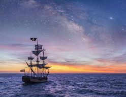 Pirate Ship leaving the harbor at the milky way sunset for a long campaign against the loyal marines on the oceans